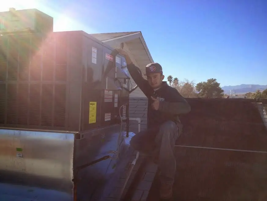 HVAC technician performing Air Duct Cleaning on a rooftop unit in Franklin